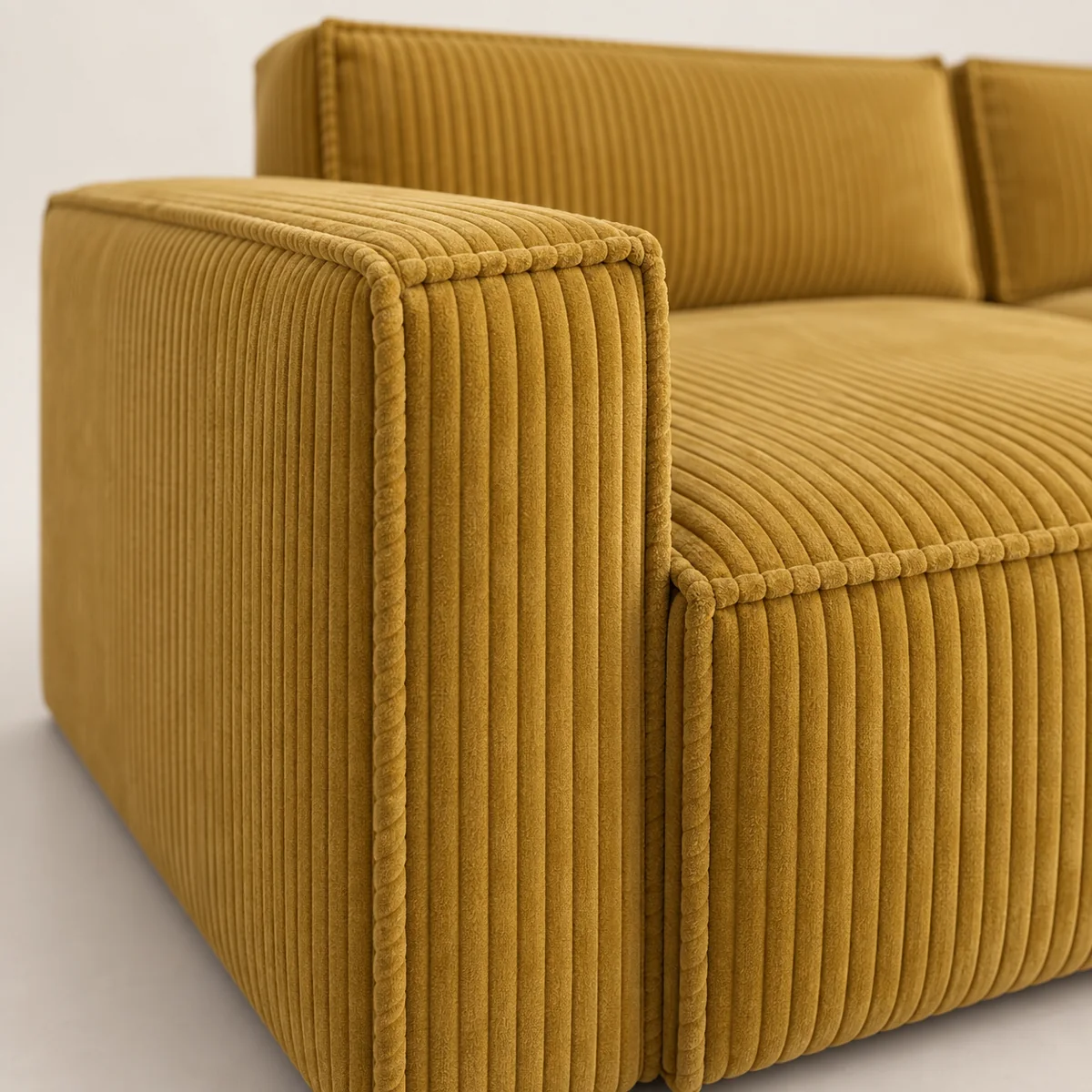 Close-up of the flanged seam on the arm of a mustard corduroy sofa